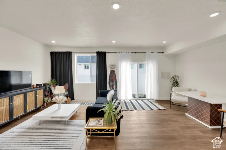Recessed lighting, wood-finish flooring, white walls, and a sliding glass door