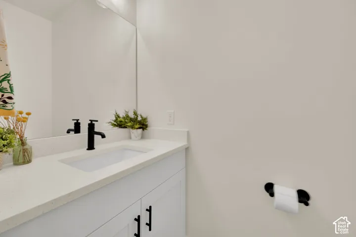White vanity with black hardware, integrated rectangular sink, and matte black faucet