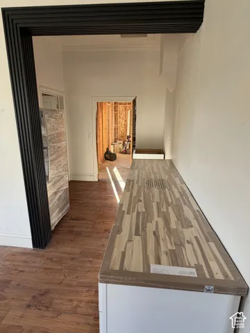 Wood-finish flooring, white cabinetry, and wood-finish countertop