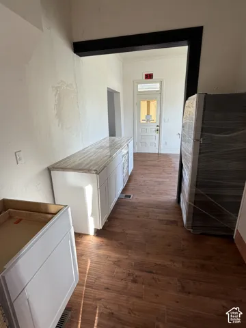 White cabinetry with a patterned countertop, wood-finish flooring, and a paneled door with transom window
