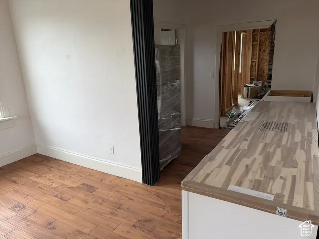 Wood-finish flooring with white baseboards, a black fluted accent wall, and a wood-finish countertop with an integrated sink