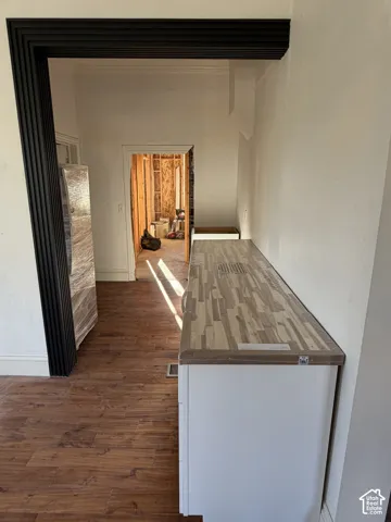 Dark-stained archway trim, wood-finish flooring, white built-in cabinetry, and a butcher block countertop