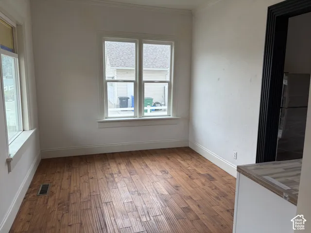 Wood-finish flooring, multiple windows, white baseboards, and crown molding