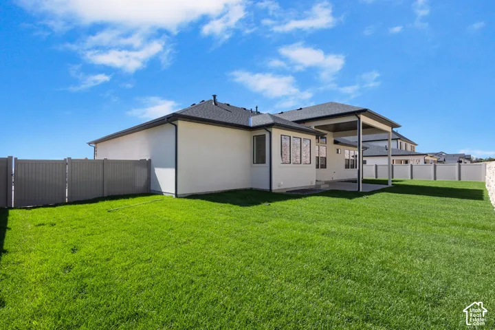 Expansive backyard featuring a manicured lawn, a covered patio, and perimeter fencing