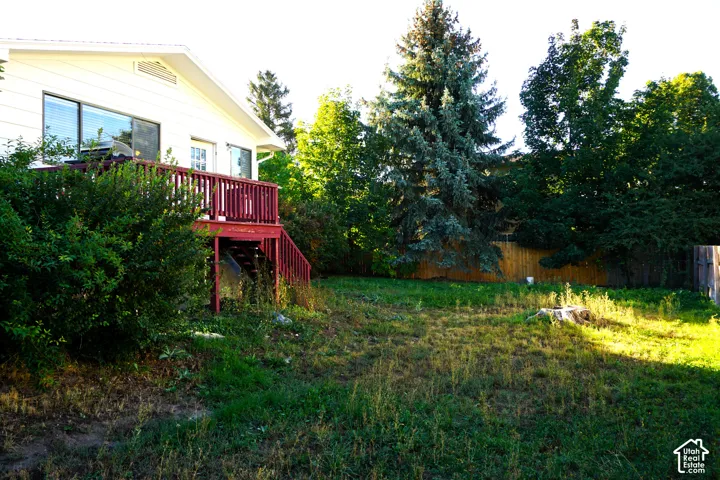 Exterior featuring a white siding, an expansive wood deck with red railings, and multiple large windows