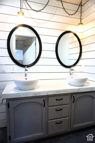 Dual vessel sinks with modern fixtures, set into a vanity with three central drawers and two cabinet doors
