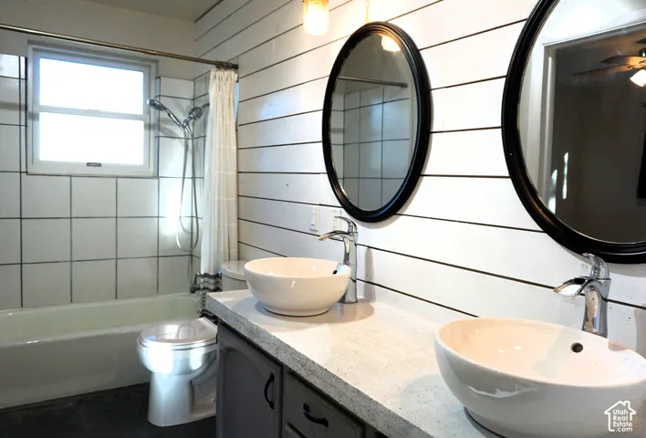 Dual vessel sinks with chrome faucets set on a light-toned countertop, white shiplap wall, and oval framed mirrors