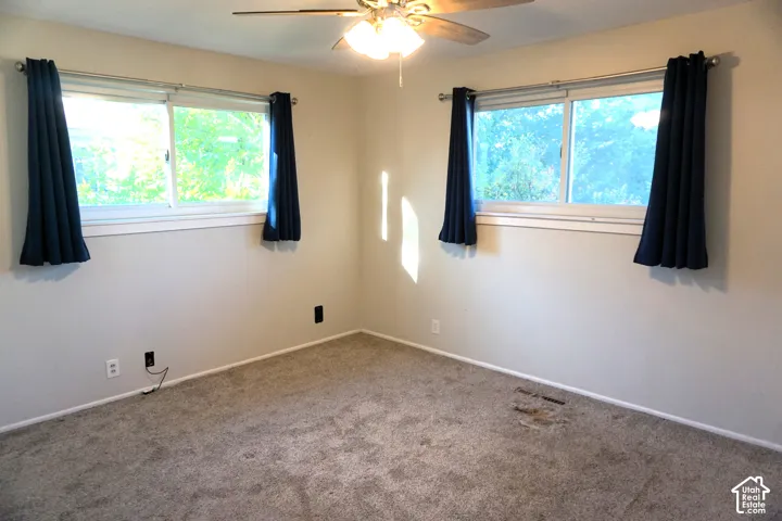 Carpeted flooring, ceiling fan with integrated lighting, and multiple windows