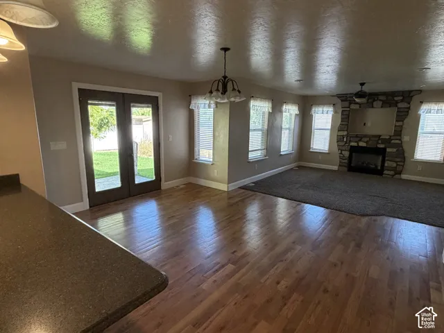 Spacious living area featuring wood-finish flooring, a stone-clad fireplace, built-in ceiling lighting, and a ceiling fan