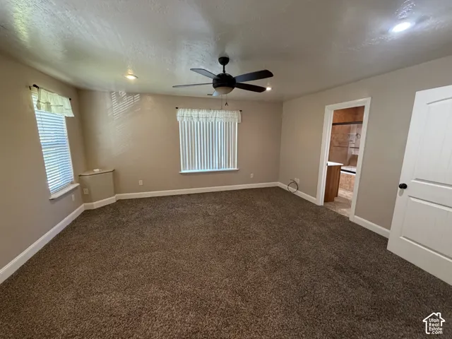 Spacious room with brown carpeting, recessed lighting, a ceiling fan, and multiple windows with blinds