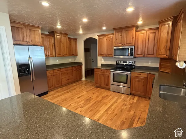 Kitchen featuring wood-finish flooring, recessed lighting, wood cabinetry, and stainless steel appliances