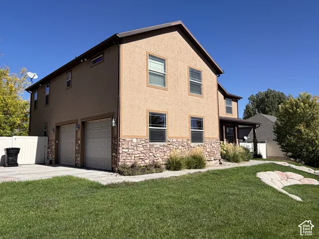 Two-story stucco exterior with stone accents, two-car garage, covered entry, and manicured lawn