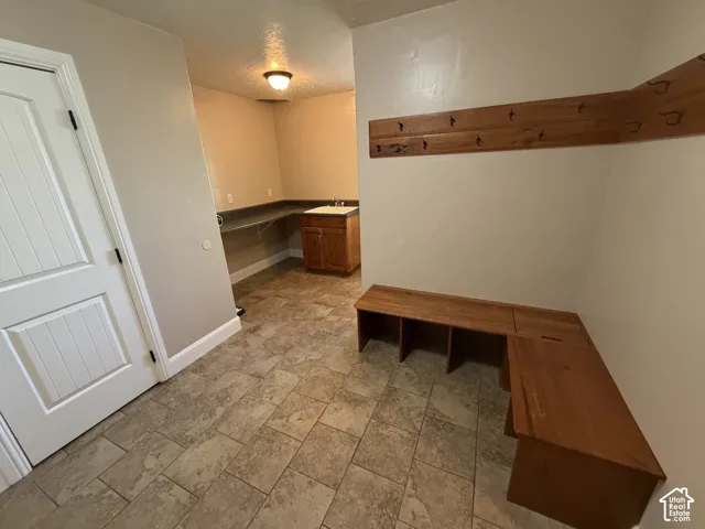Spacious utility area featuring durable tile flooring, built-in wooden bench seating, and a dedicated sink with cabinetry