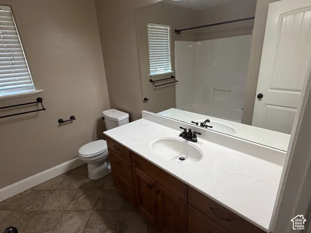 Bathroom featuring a single vanity with wood cabinetry, a white countertop, and a built-in sink with a dark-finished faucet