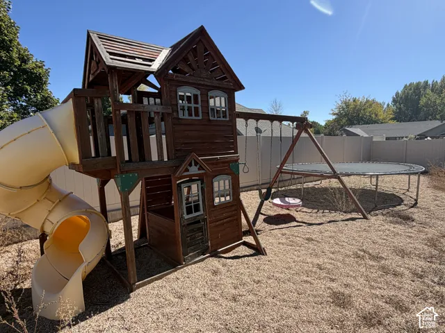 Backyard featuring a wooden playset with an enclosed slide, a swing set, and a trampoline