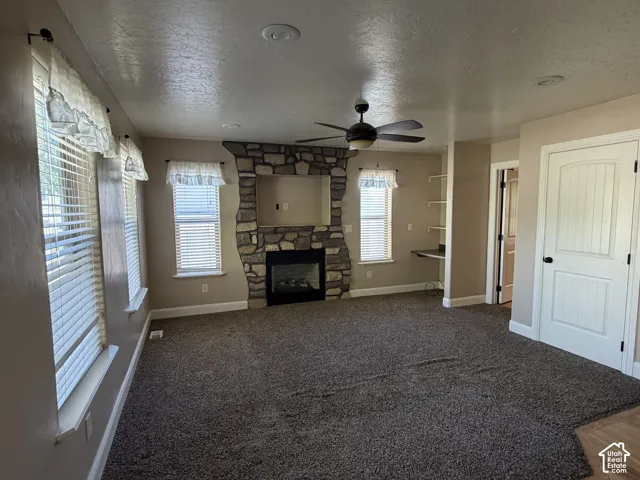 Stone-finish fireplace with an electric insert, ceiling fan, recessed lighting, built-in shelving, and light-tone walls