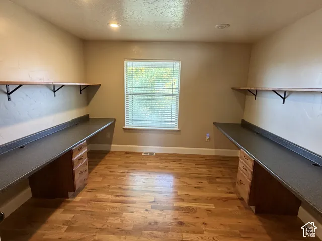 Wood-finish flooring, built-in desks with dark countertops, recessed lighting, and a window with blinds