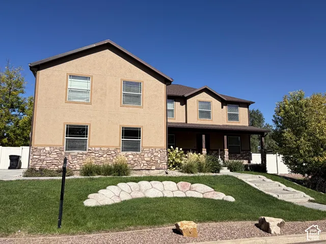 Stucco exterior with stone accent, covered front porch, and multi-pane windows