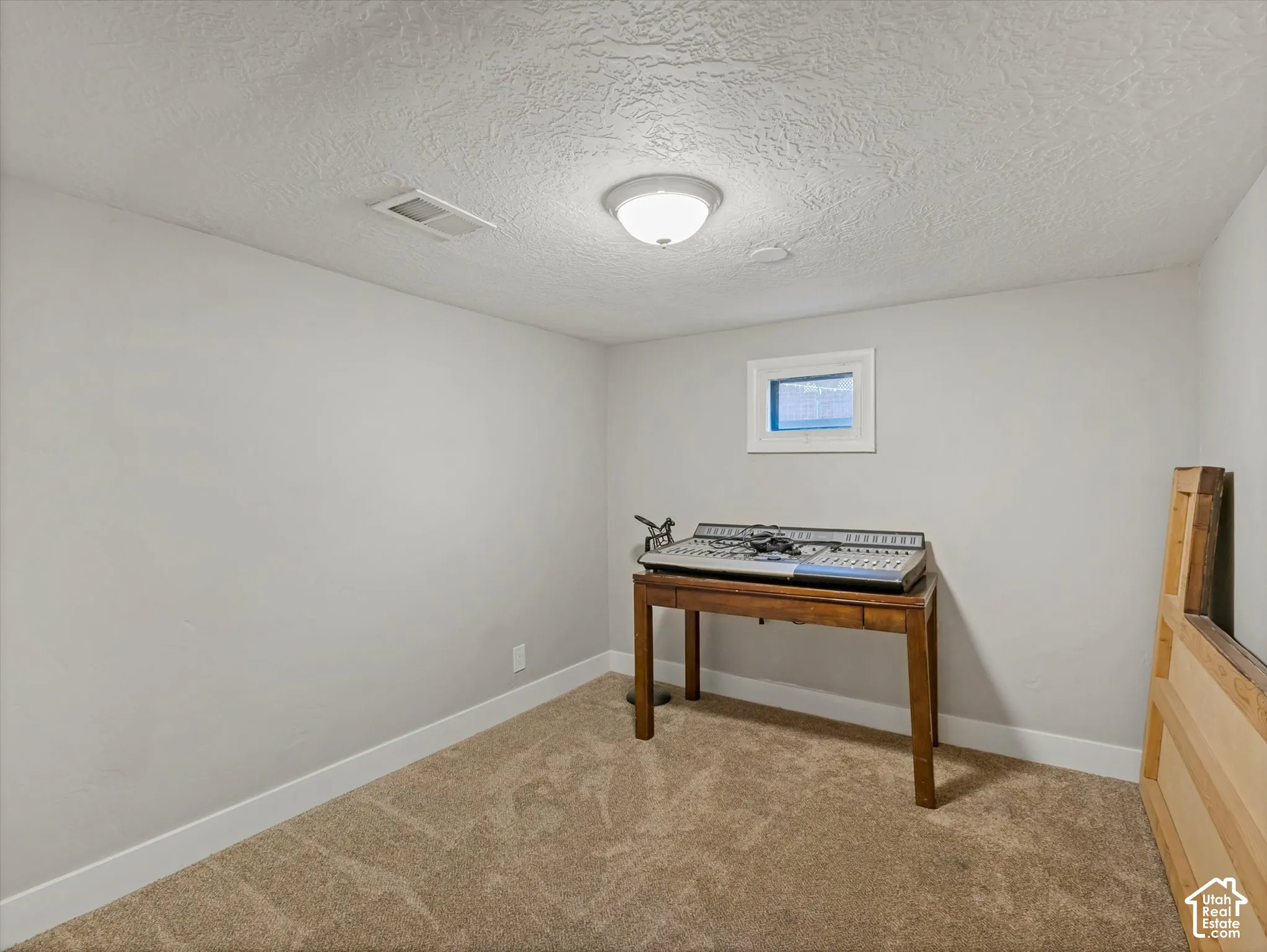 Recessed window, textured ceiling, flush mount lighting, light-colored walls, and neutral carpet flooring