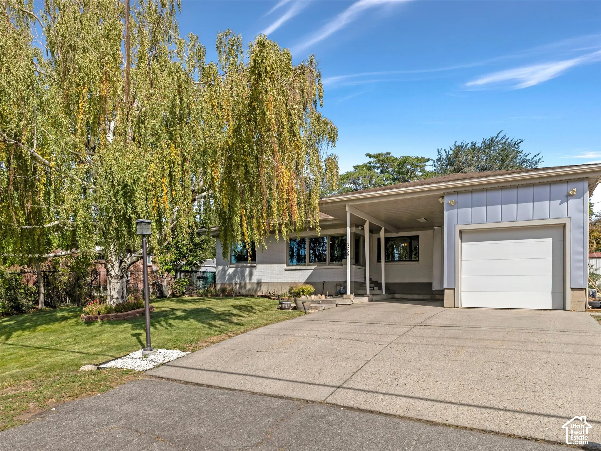 Single-story residence featuring a covered carport, attached garage, and a concrete driveway
