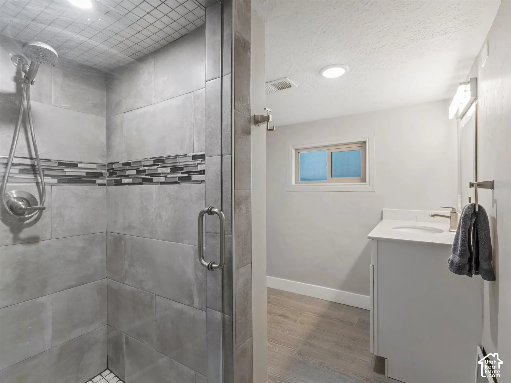 Shower with full tile surround, mosaic accent band, and glass enclosure