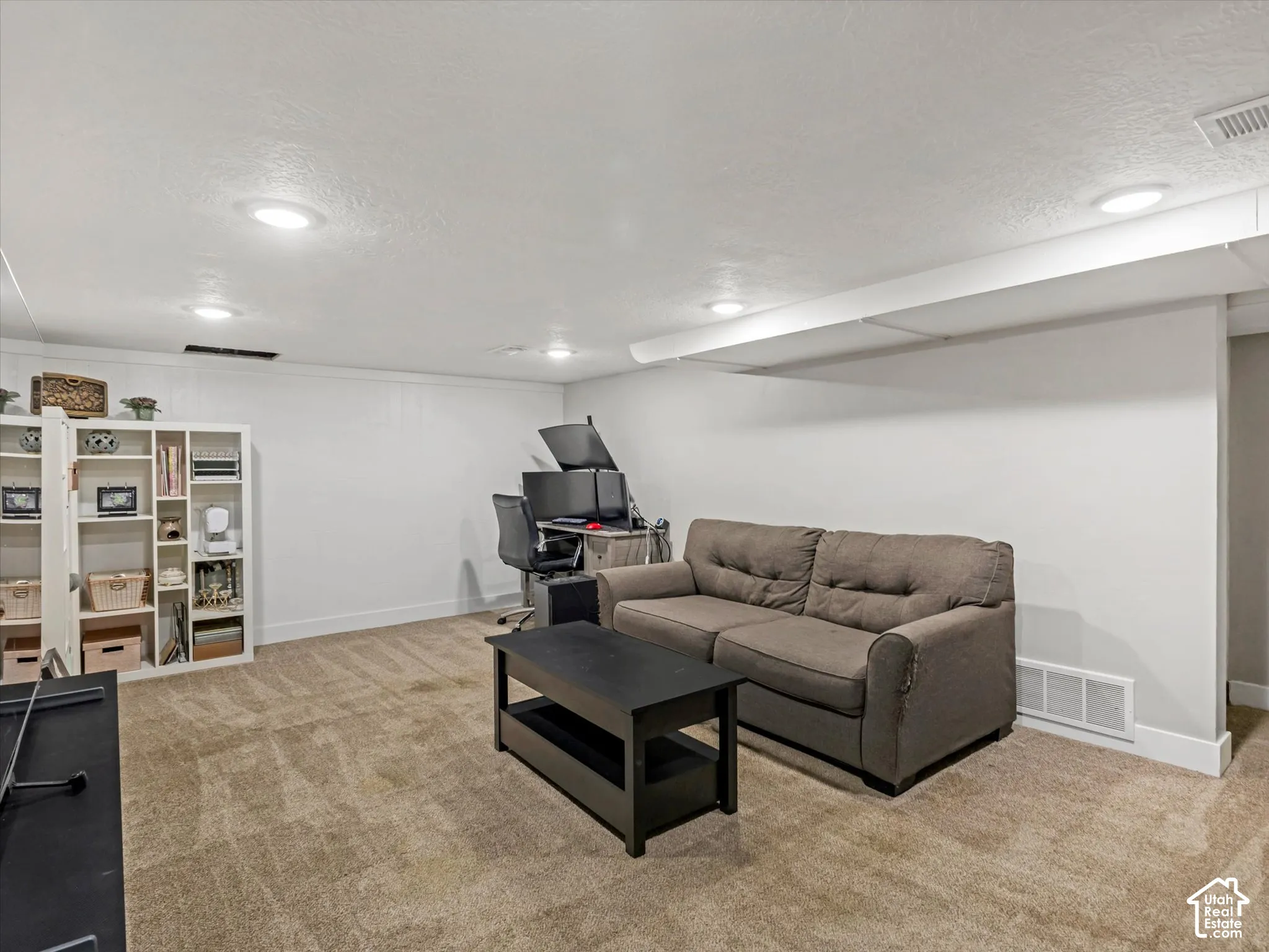 Recessed ceiling lighting, textured wall paneling, carpeting, and white baseboards