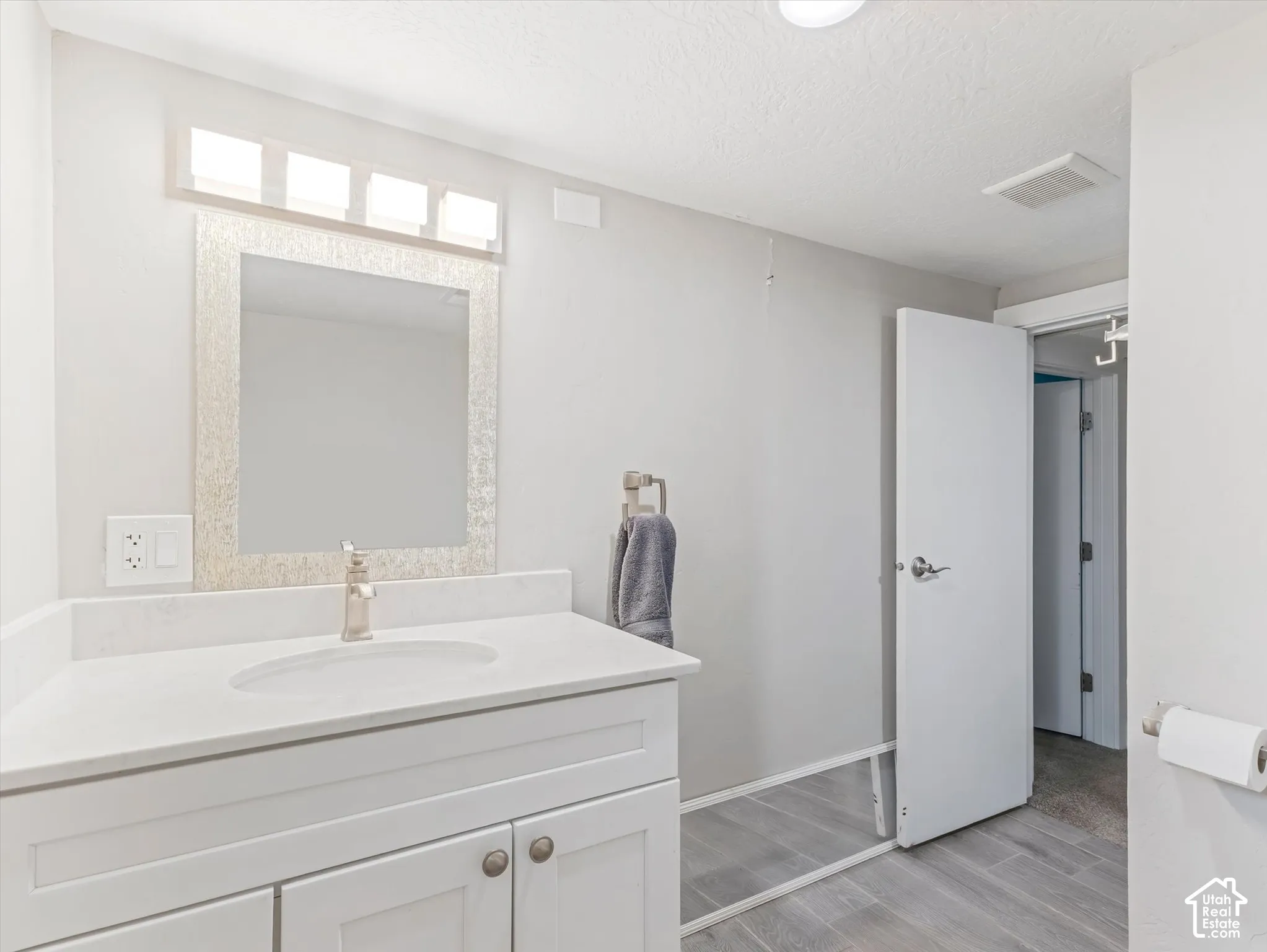 White vanity with cabinet storage, integrated rectangular sink, and light-toned countertop