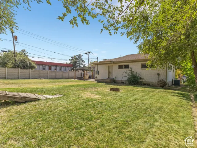 Expansive grassy yard with a concrete block privacy fence