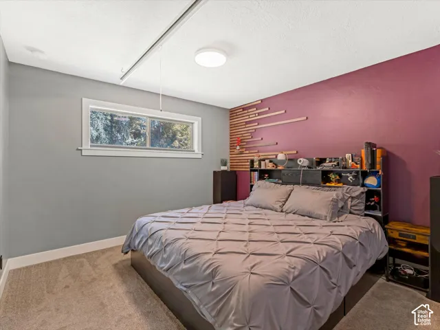Carpeted flooring, recessed ceiling light, built-in shelving, decorative wood wall paneling, and a window with white trim