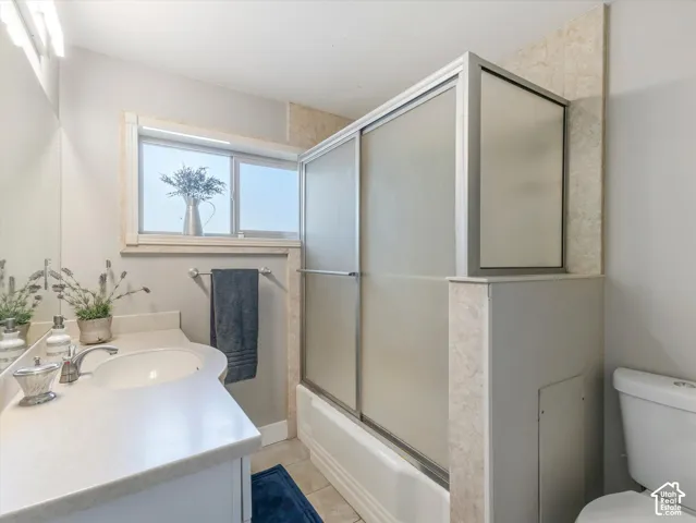 Single vanity with an integrated sink, shower-tub combination with sliding glass doors, and a window for natural light