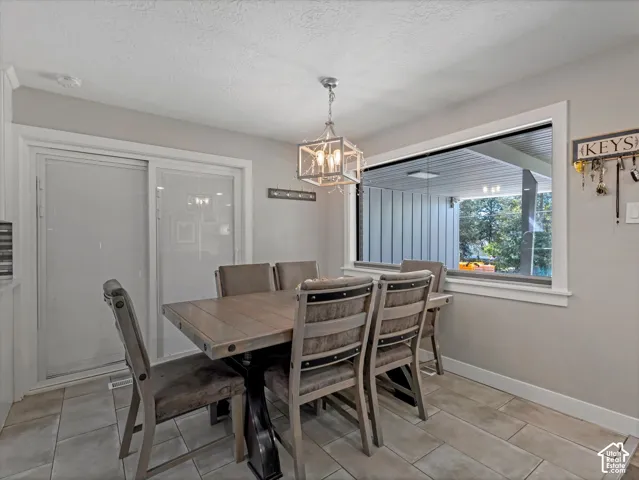 Recessed lighting and a decorative chandelier illuminate the dining area