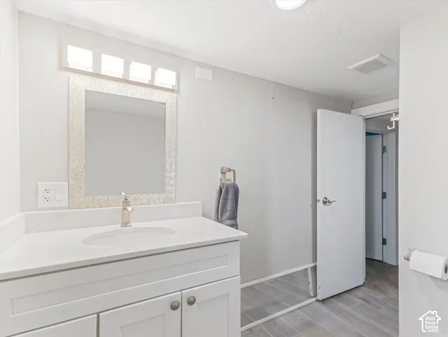 White vanity with cabinet storage, integrated rectangular sink, and light-toned countertop