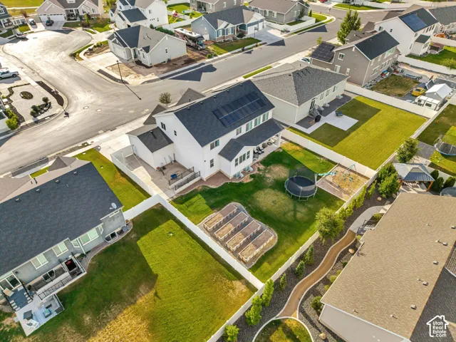 Expansive backyard with a manicured lawn, white vinyl fencing, raised garden beds, and solar panels installed on the roof
