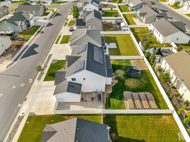 Rear exterior with solar panels, a concrete patio, and a tiered garden bed