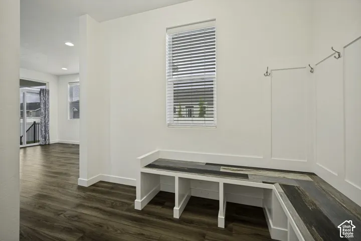 Bright mudroom featuring built-in bench seating with storage cubbies, wood-finish flooring, and abundant natural light from a large window with operable blinds