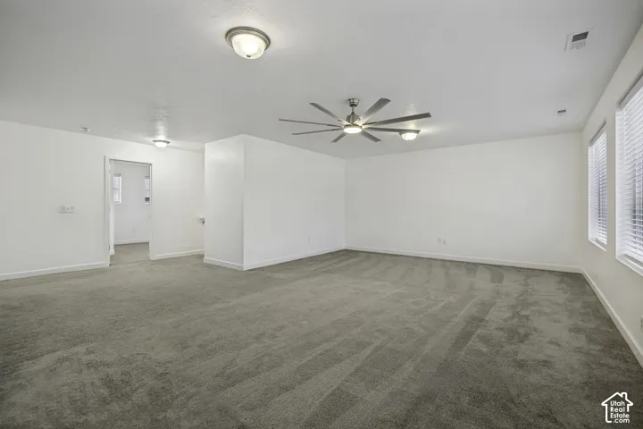 Recessed lighting, ceiling-mounted fan, multiple windows with blinds, and light gray carpet