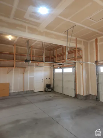 Expansive garage with a concrete floor, built-in overhead storage shelves, and two panel garage doors