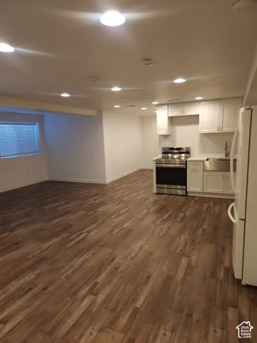 Open-concept living space featuring wood-finish flooring, recessed lighting, a window with blinds, white cabinetry, and stainless steel appliances