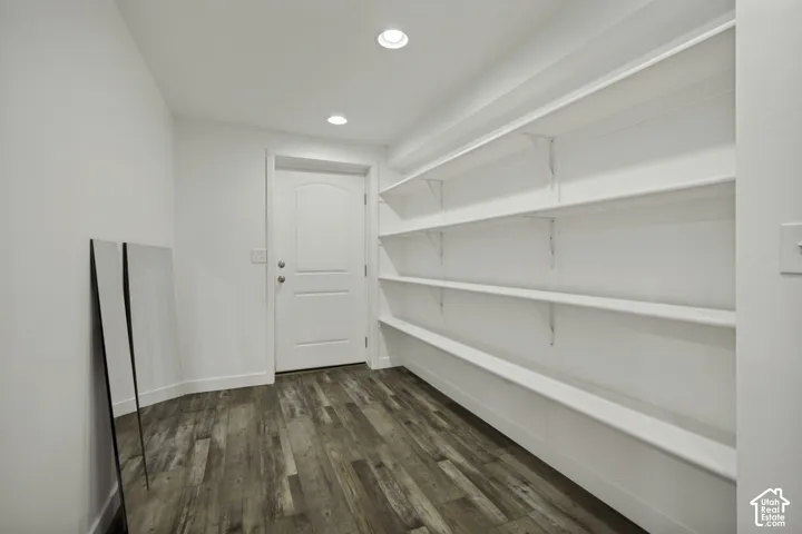 Built-in shelving, wood-finish flooring, recessed lighting, white interior door with arch detail, and white walls