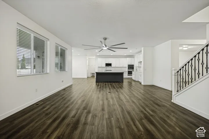 Open concept living area featuring wood-finish flooring, a modern ceiling fan, and multiple windows with blinds