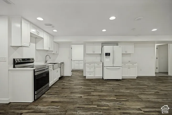 Recessed lighting, wood-finish flooring, white cabinetry, integrated sink, and stainless steel appliances