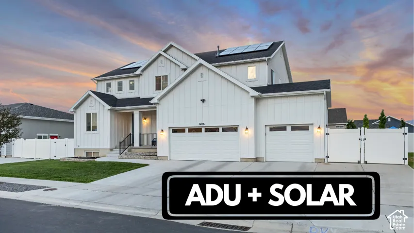 Modern farmhouse style exterior, board and batten siding, solar panels, attached three-car garage, and a white vinyl fence