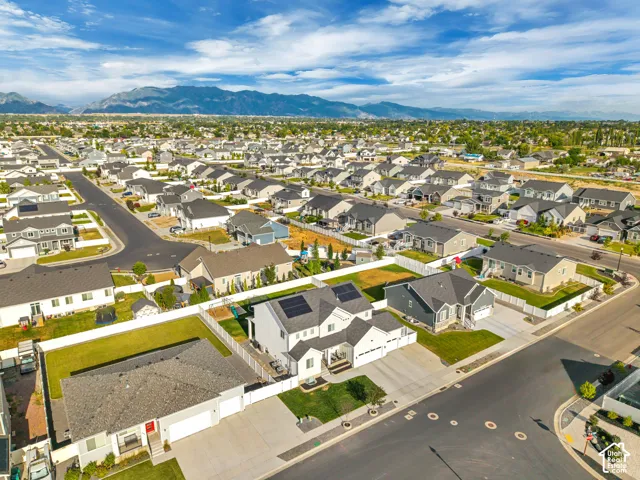 Residential neighborhood with paved streets, surrounded by distant mountains under a blue sky with clouds