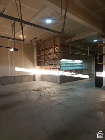 Concrete flooring, ample built-in shelving, overhead lighting, and an automatic garage door opener