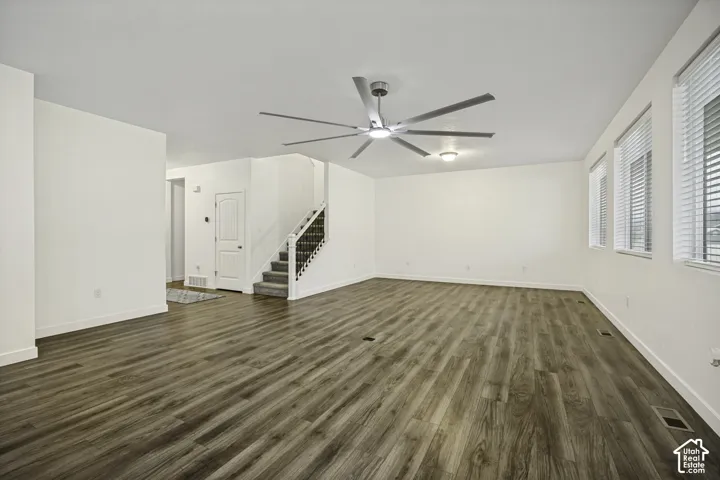 Spacious room featuring wood-finish flooring, multiple windows, a modern ceiling fan, recessed lighting, and a staircase with an iron railing