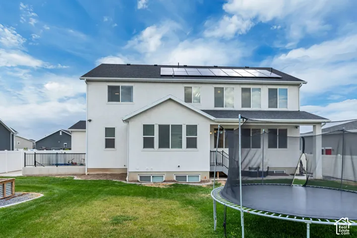 Expansive rear yard featuring a manicured lawn, white privacy fencing, and an upper-level deck