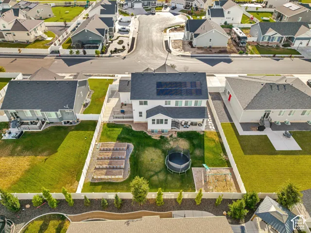 Rear exterior featuring a covered patio, solar panels, a fenced yard, and garden beds