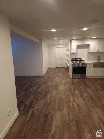 Wood-finish flooring throughout, white shaker cabinetry, stainless steel range, farmhouse sink, and recessed lighting