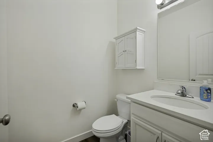 White wall-mounted cabinet, vanity with integrated sink, chrome faucet, wall-mounted mirror, and wood-finish flooring