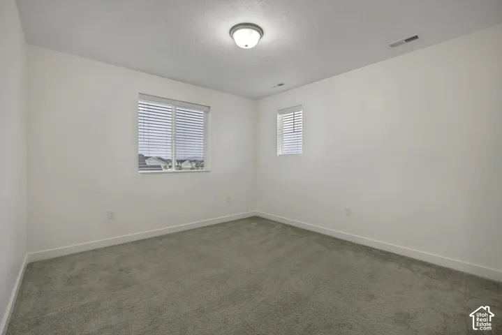 Neutral wall tones with a textured ceiling finish, recessed light fixture, and two windows featuring horizontal blinds